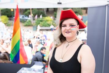 Woman wearing a red hat and the multicoloured flag painted on her cheek