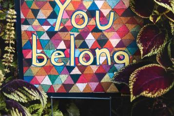 colourful fabric with the words 'you belong' sewn onto it